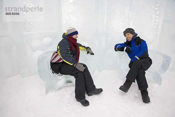 Zwei Frauen sitzen im Eishotel auf Sesseln aus Eis in Jukkasjärvi  Lappland  Nord-Schweden  Schweden