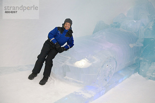 Eine Frau lehnt sich an ein Auto aus Eis im Eishotel in Jukkasjärvi  Lappland  Nord-Schweden  Schweden