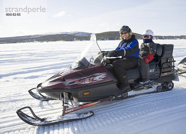 Eine Frau in den Vierzigern und ein sechsjähriges Mädchen auf einer Schneemobil-Tour in Kiruna  Lappland  Nord-Schweden  Schweden