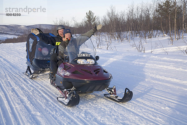 Eine Frau und ein Mann in den Vierzigern auf einer Schneemobil-Tour in Kiruna  Lappland  Nord-Schweden  Schweden