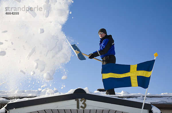 Ein Mann schippt Schnee vom Dach seines Hauses in Kiruna  Lappland  Nord-Schweden  Schweden
