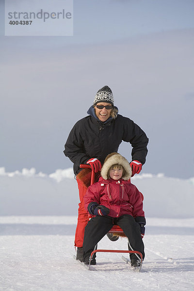 Vor dem Eishotel fahren eine Frau und ein vierjähriges Mädchen auf einem Schlitten  Jukkasjärvi  Lappland  Nord-Schweden  Schweden
