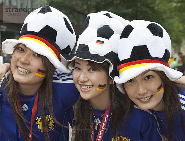 Drei weibliche japanische Fußballfans posieren gut gelaunt mit Kopfbedeckungen und Stickern in deutschen Landesfarben vor dem Spiel der Fußball-Weltmeisterschaft 2006 Japan gegen Brasilien  1:4  in Dortmund  Nordrhein-Westfalen  Deutschland