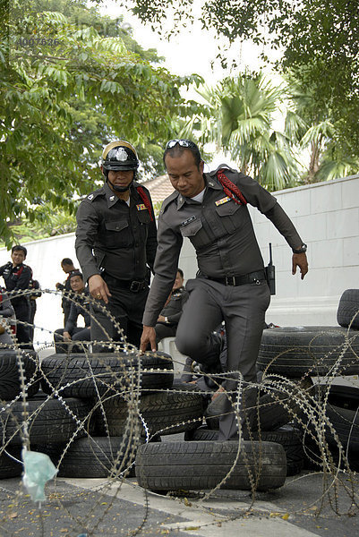 Demonstration  Polizisten versuchen Straßensperre mit Stacheldraht und Autoreifen zu überwinden  Bangkok  Thailand  Südostasien  Asien