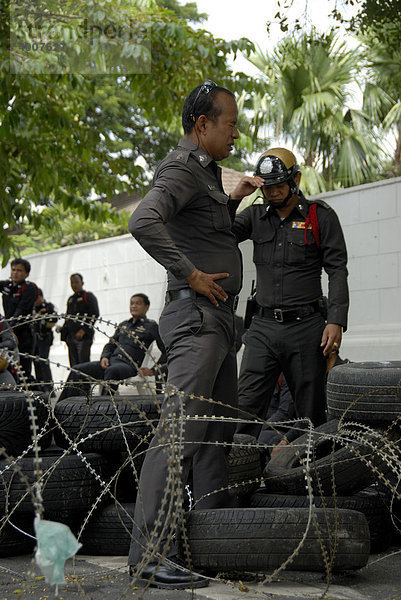 Demonstration  Polizist steht in Straßensperre mit Stacheldraht und Autoreifen  Bangkok  Thailand  Südostasien  Asien
