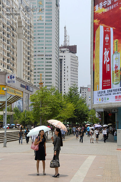 Zwei Frauen mit Schirm  belebte Fußgängerzone im modernen Stadtzentrum  Kunming  Provinz Yunnan  Volksrepublik China  Asien