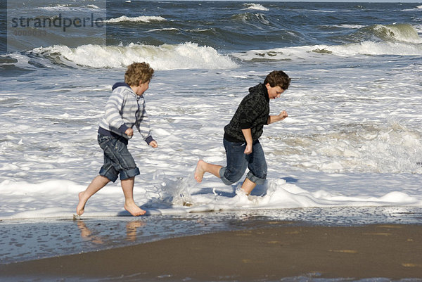 2 Jungen werden von einer Welle überrascht an der Nordseeküste von Holmesland  Jütland  Dänemark  Europa