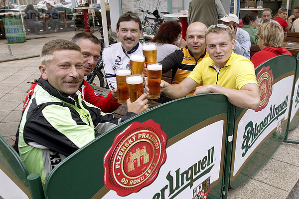 Radfahrer  Männer  stossen in einem Biergarten auf dem Platz der Republik mit einem Bier an  Pilsner Urquell  an in Pilsen  Plzen  Böhmen  Tschechien  Europa.