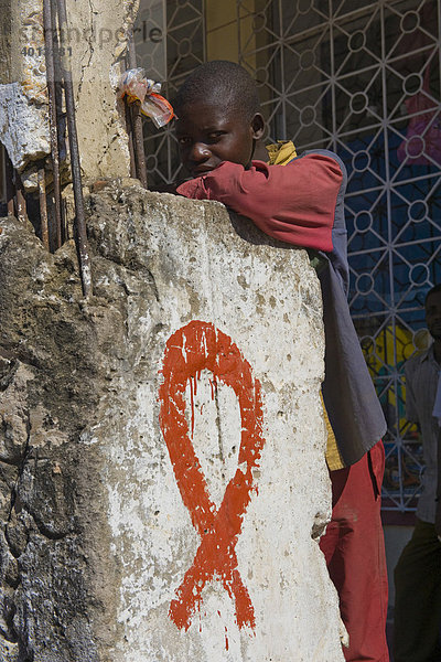Straßenkind und Rote Schleife  Red Ribbon  das weltweite Symbol der Solidarität mit HIV-Infizierten und AIDS-Kranken  Quelimane  Mosambik  Afrika