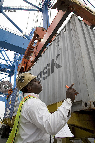 Ein Hafenarbeiter lenkt einen Kranführer beim Aufheben eines Containers  der auf ein Schiff im Hafen von New Orleans geladen werden soll  New Orleans  Louisiana  USA