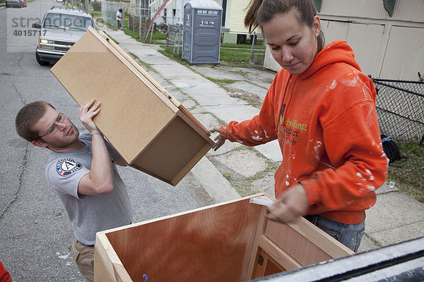 Freiwillige des Americorps laden Küchenschränke von einem Lastwagen ab während sie ein Haus renovieren  das vom Hurrikan Katrina beschädigt wurde  Lower Ninth Ward Bezirk  New Orleans  Louisiana  USA
