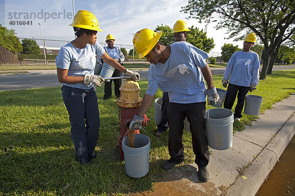 High-School-Schüler füllen Wassereimer an einem Feuerhydranten  um neu gepflanzte Bäume zu wässern  im Rahmen ihrer Sommerjobs im Conservation Leadership Corps  Detroit  Michigan  USA