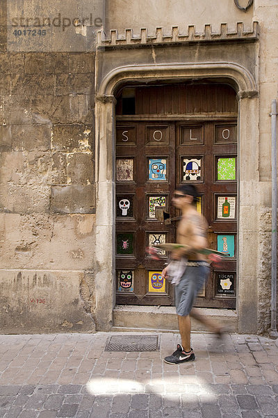 Spanischer Mann mit Skateboard vor Tür mit Kunstwerk von Albert Pinya  Calle Sant Feliu  Palma de Mallorca  Mallorca  Balearen  Spanien