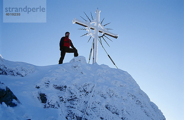 Ein Mann am Gipfelkreuz des Steinernen Jäger in den Voralpen bei Reichraming im Winter  Oberösterreich  Österreich  Europa