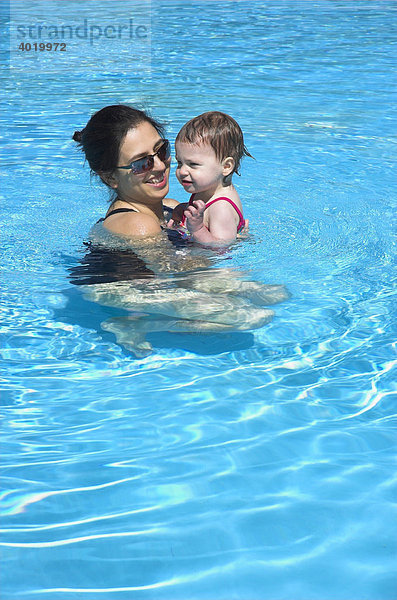 Eine junge Mutter spielt mit ihrer kleinen Tochter in einem Schwimmbecken