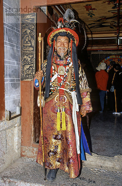 Naxi Dongba Schamane in traditioneller Kleidung  hält Pfeife  Lijang  historische Hauptstadt des Naxi-Königreichs  UNESCO Weltkulturerbe 1997  Yunnan  China  Asien