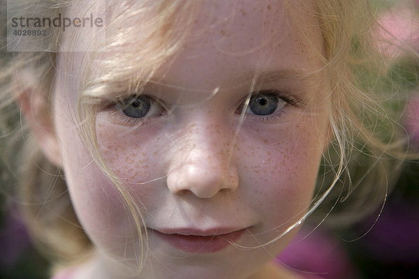 Porträt eines sommersprossigen Mädchens  5-10 Jahre  im Blumengarten