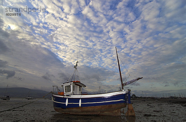 Ein Boot am Hafen von Beaumaris bei Ebbe  vor wolkigem Himmel  Beaumaris  Wales  Vereinigtes Königreich  Europa