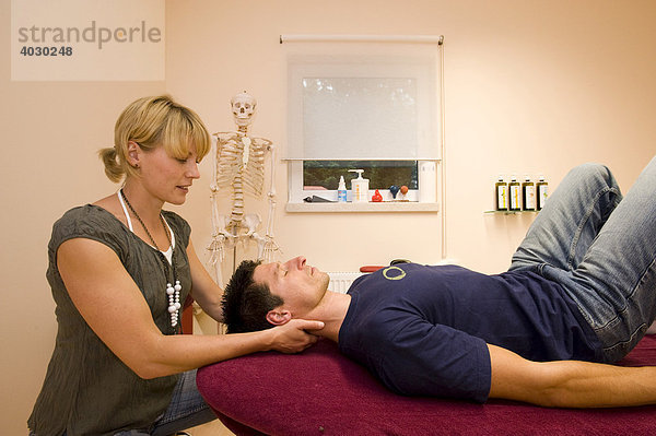 Physiotherapeutin  Lehrerin für Alexandertechnik führt mit einem Patienten eine Entspannungsübung für den Hals-Nacken-Bereich im Praxisraum durch