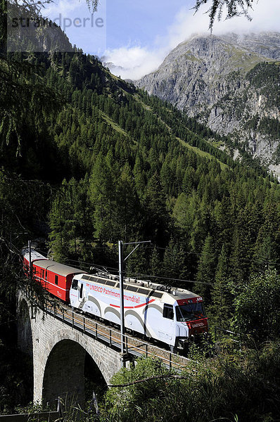 Ein Zug der Rhätischen Bahn RhB fährt auf der Albula-Strecke zwischen Bergün und Preda auf einem Viadukt  Graubünden  Schweiz  Europa