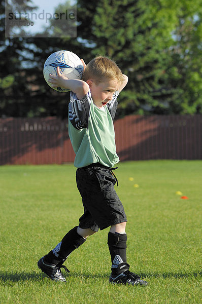 6-jähriger Junge macht in einem Fußballspiel für unter 8-jährige einen Einwurf