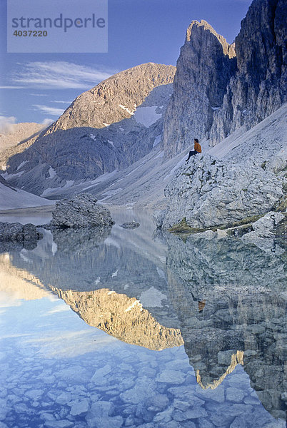 Wanderer sitzt am Bergsee Lago di Antermoia  Rosengarten  Südtirol  Italien  Europa