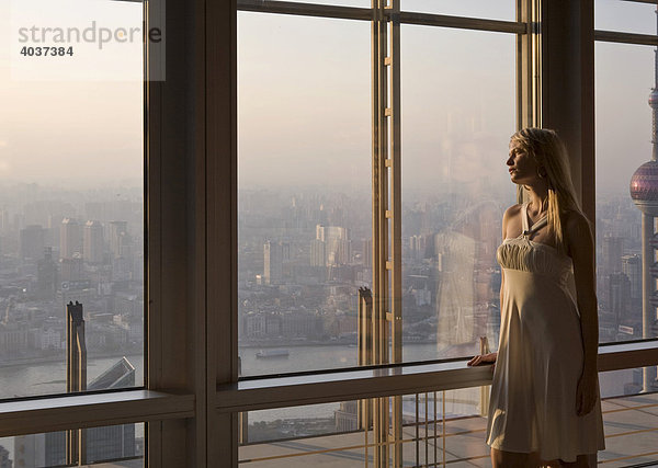 Junge Frau schaut aus dem Fenster auf Skyline  Shanghai  China  Asien