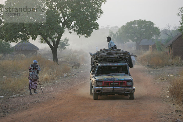 Schwer beladenes Auto auf der Dorfstraße  im morgendlichen Dunst  Houssere Faourou  Kamerun  Afrika