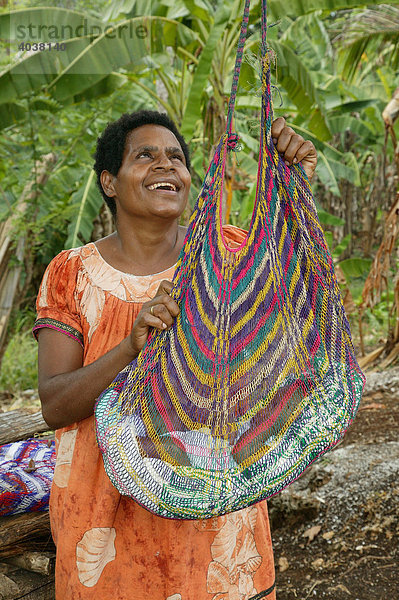 Frau mit Säugling im Bilum  typische Tasche in PNG  hängt am Ast eines Baumes  Logaweng  Papua Neuguinea  Melanesien