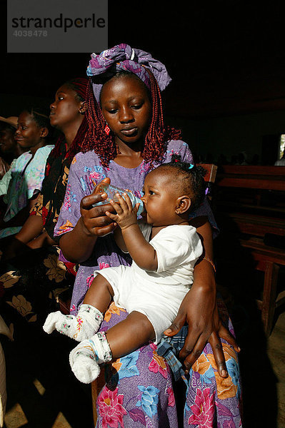 Frau füttert Kleinkind mit Fläschchen  während des Gottesdienstes  Manyemen  Kamerun  Afrika