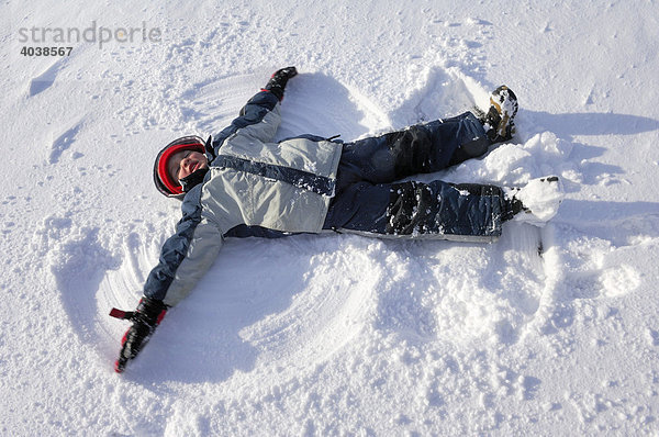 Ein Kind liegt im Schnee und formt einen Schneeengel  Schliersee  Oberbayern  Bayern  Deutschland  Europa