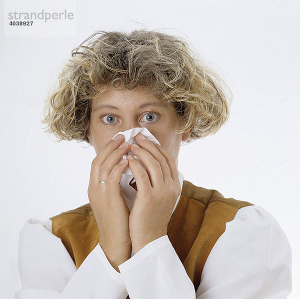 Blonde Frau putzt sich die Nase mit Papiertaschentuch