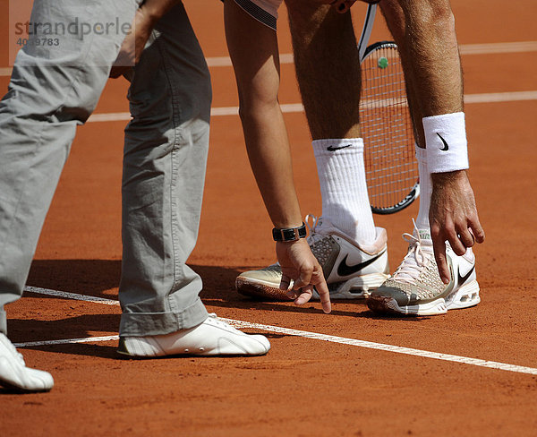 Umstrittene Schiedsrichterentscheidung beim Tennis  Schiedsrichter zeigt Tennisspieler mit Zeigefinger der linken Hand auf Linie des Tennisplatzes  die der Ball berührt haben soll