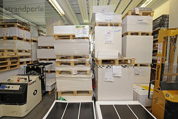 Verschiedene Papiersorten gestapelt auf Paletten in der Halle einer Druckerei