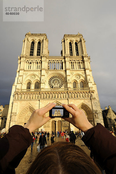 Touristin mit Digitalkamera fotografiert Notre Dame de Paris mit Hauptportal  Westansicht  Paris  Frankreich  Europa
