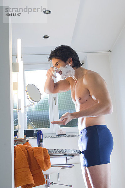 Mann in Unterhosen rasiert sich im Bad