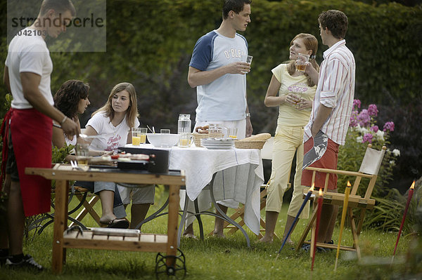 Gruppe junger Leute beim Barbecue im Garten