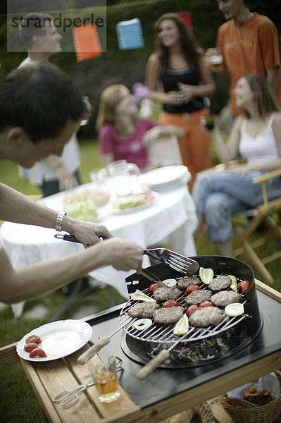 Gruppe junger Leute beim Barbecue im Garten