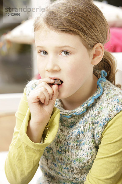 8-jähriges Mädchen isst Schokolade  mit schlechtem Gewissen