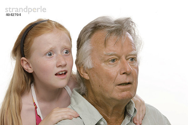 8-jähriges Mädchen mit roten Haaren umarmt ihren Großvater  beide erschrocken