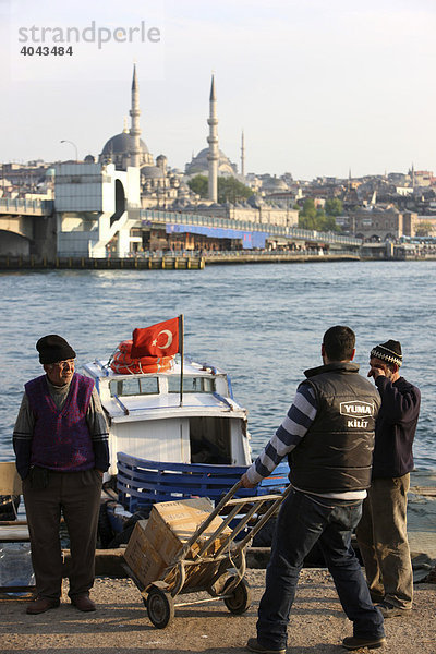 Männer beim Beladen  türkische Flagge  kleine Flußfähre  Bootstaxi am Goldenen Horn  neben der Galatabrücke  Istanbul  Türkei