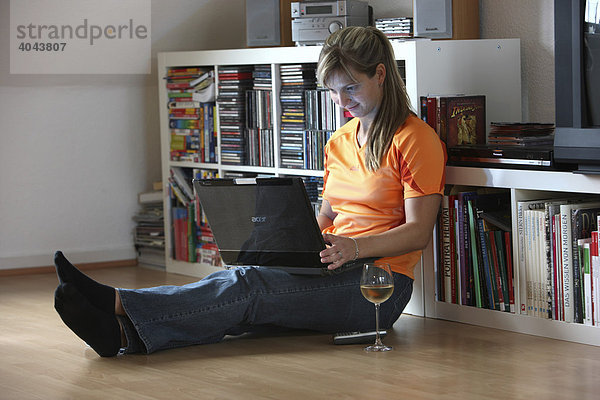 Junge Frau  25-30 Jahre  surft im Internet mit Laptop Computer in ihrer Wohnung