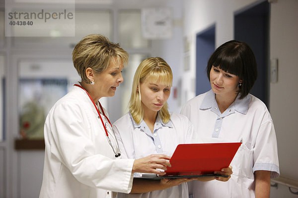 Ärztin bei einer Besprechung mit zwei Krankenschwestern auf dem Flur einer Krankenstation in einem Krankenhaus