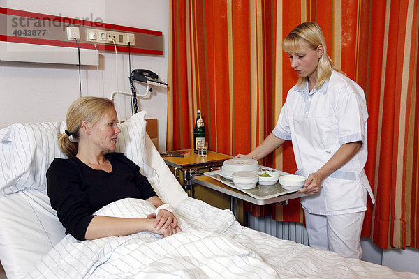 Krankenschwester bringt einer Patientin das Essen ans Bett im Krankenhaus