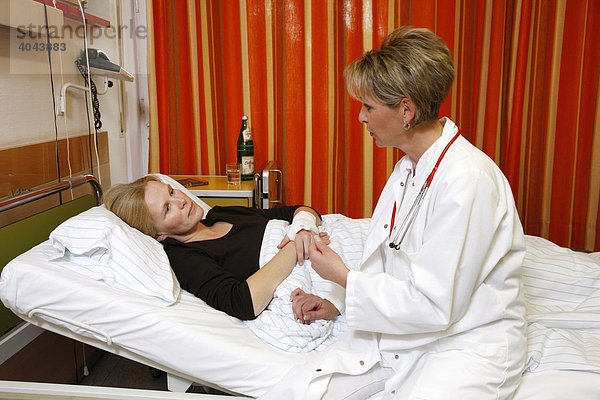 Ärztin spricht mit einer Patientin am Krankenbett im Krankenhaus