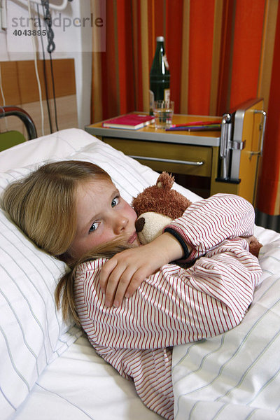 Mädchen  7 Jahre  mit Teddy im Bett im Krankenhaus