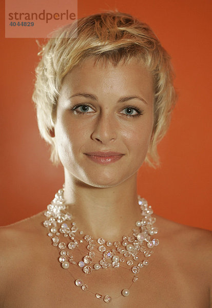 Porträt einer jungen blonden Frau mit Schmuck und Kurzhaarschnitt