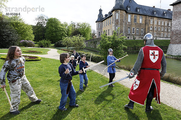 Kinder spielen Ritter  kämpfen mit Schwertern gegen einen Mann in Ritterkleidung  Renaissancefest  Wasserschloss Dyck  Jüchen  Rheinland  Nordrhein-Westfalen  Deutschland  Europa