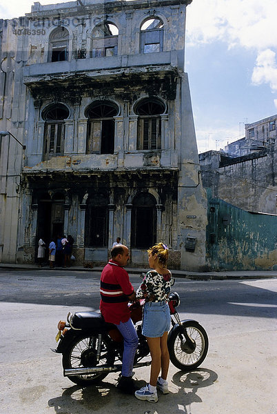 Frau spricht Mann auf Motorrad an  Straßenszene vor Hausruine  San Laz·ro  Centro Habana  Havanna  Kuba  Karibik