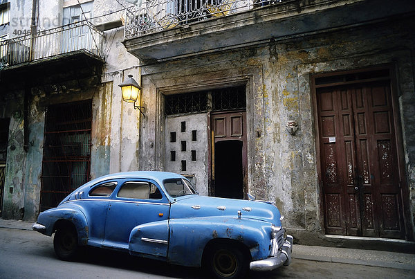 US-Oldtimer parkt vor einem verfallen Haus in der Altstadt  abends  La Habana Vieja  Havanna  Kuba  Karibik
